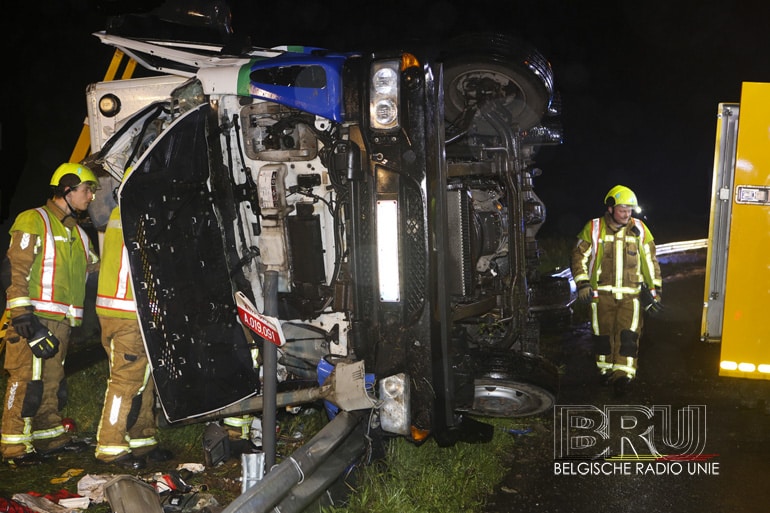 Vrachtwagen maait verlichtingspaal omver en kantelt, bestuurder gekneld